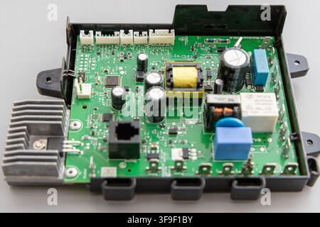 A green electronic circuit board displays various components mounted in a black casing Stock Photo