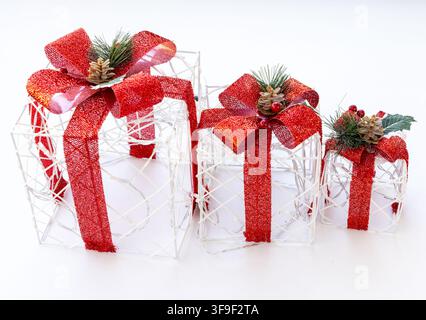 Three glowing white wire gift boxes with red bows sit on white Stock Photo