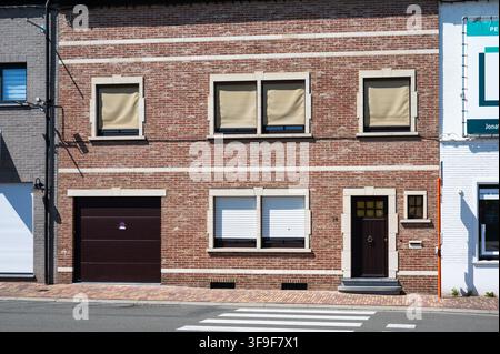 A traditional brick terraced house in Nederbrakel with closed roller shutters and external sun shades on the windows. Nederbrakel, Brakel, Belgium 13 Stock Photo