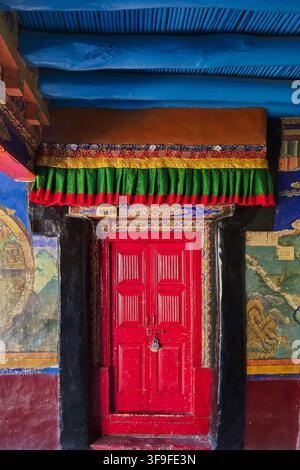 Red door in Buddhist monastery interior with Tibetan murals, traditional art and architecture in Leh, Ladakh, India Stock Photo