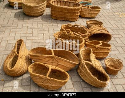 Various traditional handwoven wicker and esparto grass baskets are arranged on a stone pavement. They showcase different shapes and sizes. This busy m Stock Photo