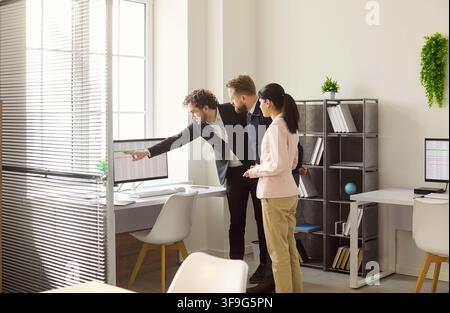 Business team discussing data analysis at monitor in modern office workspace Stock Photo