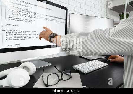 Programmer pointing at computer screen with code, software development and web programming concept, modern office workspace Stock Photo