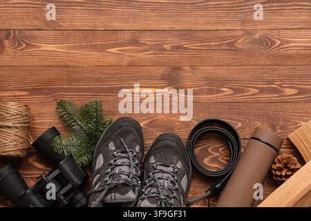 Composition with shoes for hiking, belt, thermos and binoculars on wooden background Stock Photo