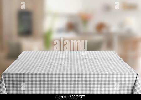 Empty kitchen table with gray and white checkered tablecloth, blurred home interior background, this image offers ample copy space for text or additio Stock Photo