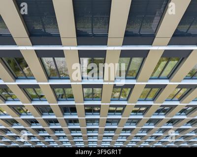 Aerial view of the repetitive geometric facade of a modern office building with rows of windows and beige structural panels in Poland. Stock Photo