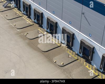 Aerial view of a modern logistics hub featuring multiple numbered loading docks and paved yard with yellow safety markings in Poland. Stock Photo