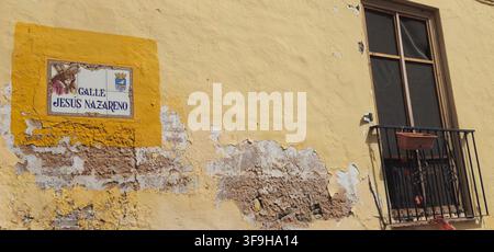 Calle Jesús Nazareno ceramic street sign on a weathered yellow facade with a wrought iron balcony in Almuñécar, Andalusia, Spain. Stock Photo