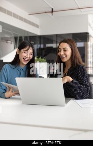 Women colleagues working on joint task using tablet and laptop Stock Photo