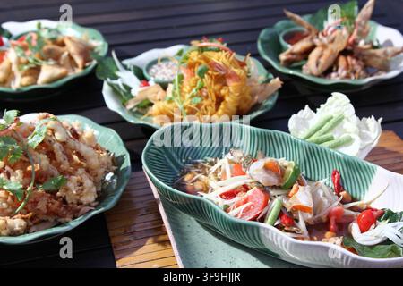 A spread of various traditional Thai dishes including papaya salad and fried items arranged on a table. Stock Photo