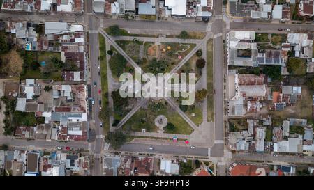 Aerial view of Plaza Independencia with its central cross-shaped walkways, green lawns, and surrounding urban residential blocks in San Jose de Felici Stock Photo