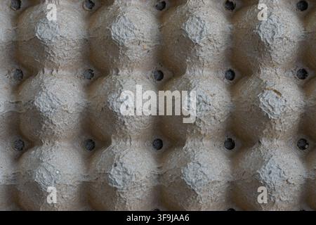 Close-up view of an empty recycled cardboard egg tray showing its repeating geometric compartments, textured paper surface and small ventilation holes Stock Photo
