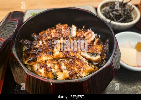 Close-up on a serving of delicious traditional unagi donburi in Japanese restaurant. Consist rice, topped with grilled unagi with gravy. Stock Photo