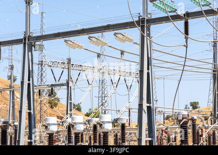 A complex network of power lines, transformers, and insulators at an outdoor electrical substation on a sunny day Stock Photo