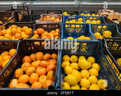 Assorted citrus fruit stored in stacked containers within a local supermarket, providing a vibrant selection of raw ingredients and fresh produce for Stock Photo