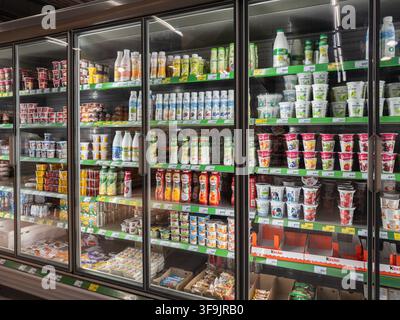 Kyiv, Ukraine - March 14, 2026: Various milk bottles and yogurt cups displayed on cold grocery refrigerator shelves, showcasing a neat retail environm Stock Photo