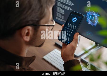 Close up of man using AI chatbot app on his smartphone for business tips while artificial intelligence assistant or agent on his computer helps him with work and daily tasks on background. Copy space Stock Photo