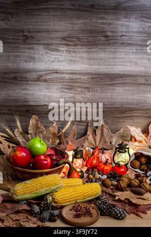 Autumn harvest arrangement with apples, corn, pumpkins, and dried leaves on a rustic background Stock Photo