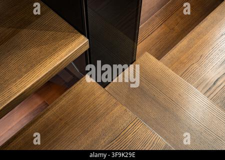 Abstract close-up of wooden staircase steps with rich grain texture and geometric angles, interior architecture detail Stock Photo