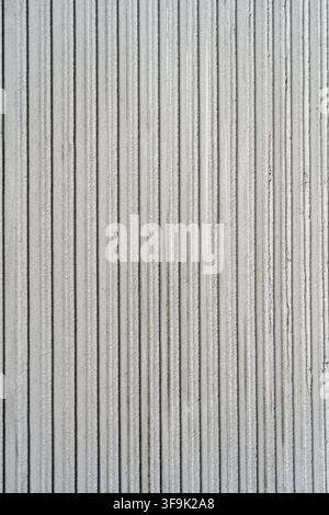 Minimalist vertical grooved plaster wall texture in light gray, detailed architectural surface with repetitive linear pattern for interior design Stock Photo
