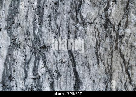 Close-up of rough gray stone wall texture with natural cracks, weathered surface and monochromatic mineral patterns for architectural and construction Stock Photo