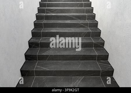 Modern dark marble staircase with large-format stone tiles, freshly renovated walls and clean minimalist interior design in a contemporary building Stock Photo