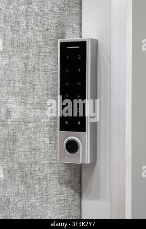 Modern electronic keypad door lock with numeric touch panel and fingerprint sensor installed on a contemporary interior door, smart home security tech Stock Photo