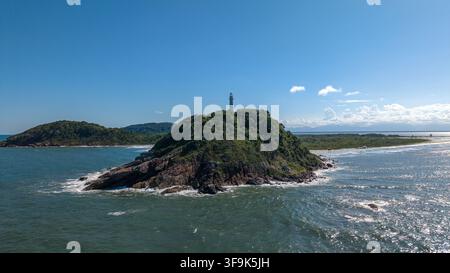 Aerial view of the Lighthouse of the Shells situated on a lush green island surrounded by the blue ocean and rocky coastline in Paranagua, Parana, Bra Stock Photo