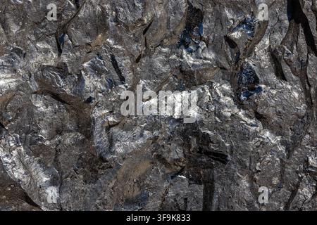 Detailed close-up captures rugged texture of coal. Sharp edges and deep fissures contrast with bright highlights and dark matte areas. Stock Photo