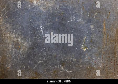 Full-frame background features a dark, textured metal surface with scratches, scuff marks, and rust stains. The imperfections and organic patches high Stock Photo