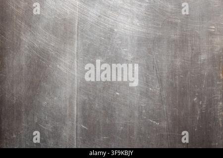 Close-up view of a brushed Stainless Steel surface showcasing fine scratches and variations in tone. The texture conveys a sense of industrial wear an Stock Photo