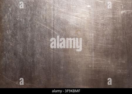 Close-up of a textured Stainless Steel surface showcasing fine scratches and smudges. The aged appearance and lighting create a dramatic, industrial a Stock Photo