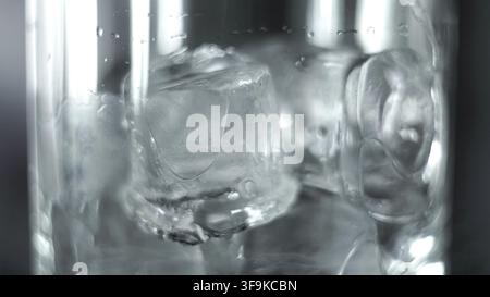 Ice cubes dissolve ina clear glass, forming a cool drink while condensation gathers and water droplets bead on the surface Stock Photo