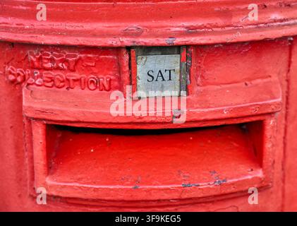 Detail of a rural traditional red UK postbox saying the next collection is due on Saturday Stock Photo