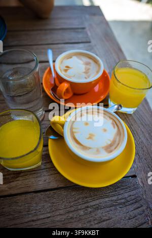 Cups of latte art and juice served on a wooden table Stock Photo