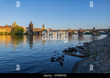 Charles Bridge across Vltava River in city of Prague, Czech Republic. Medieval stone arch bridge at sunset. Stock Photo