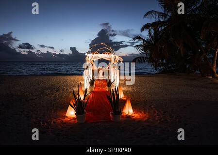 Illuminated romantic dinner setup on a beach at night in Maldives Stock Photo