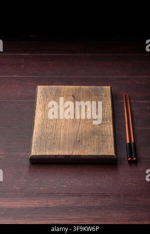A square wooden cutting board for home food preparation. A wooden cutting board serving as a food background for your design Stock Photo