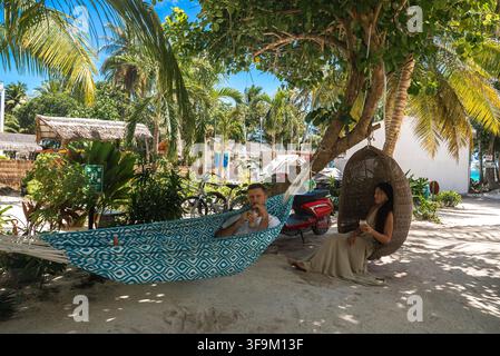 Couple relaxing in hammock and hanging chair on Dhigurah island Stock Photo
