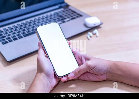 A person is holding a cell phone in their hand. The phone is white and has a keyboard on the back Stock Photo
