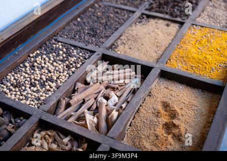 assorted colorful spices and herbs displayed in divided wooden tray at traditional market in Morocco, selective focus Stock Photo