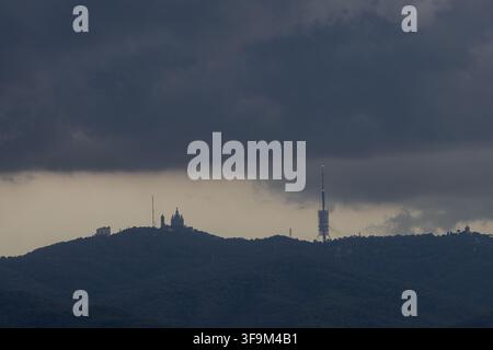 Dark storm clouds gather over the Collserola mountain range in Barcelona, Catalonia, Spain, with the Temple Expiatori del Sagrat Cor on Tibidabo and t Stock Photo