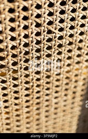 Detailed close up of natural woven rattan cane webbing texture with selective focus on furniture in warm bright light. Stock Photo