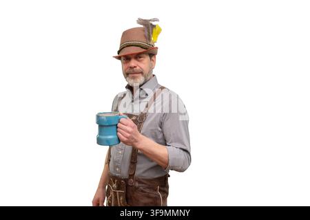 A mature bearded man wearing a Bavarian-style outfit holds a blue beer mug on a white background. Stock Photo