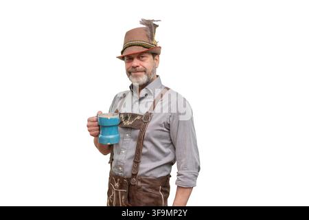 A smiling middle-aged man in Bavarian-style clothing holds a blue tankard against a light background. Stock Photo