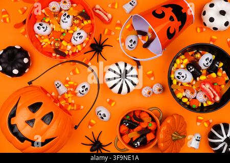 Halloween trick or treat scene with jack o lantern pails and a variety of candy. Top view on an orange background. Stock Photo
