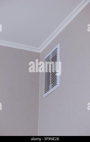 Modern white ventilation grill installed in the corner of a clean interior room wall and ceiling Stock Photo