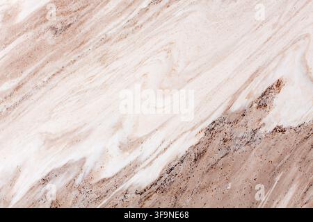 Detail of a natural marble surface where pale cream layers meet warm brown mineral streaks, creating a smooth diagonal veined pattern useful as a desi Stock Photo