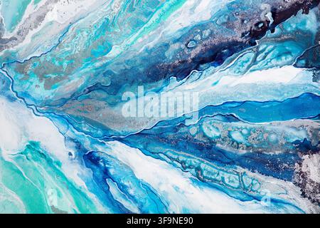 Close up of an abstract acrylic pour painting where blue, teal and white pigments blend into marbled waves, veins and cells resembling water seen from Stock Photo
