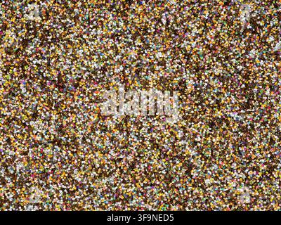 Overhead view of thousands of small round paper confetti pieces covering the entire surface, creating a bright festive texture for celebration themes. Stock Photo